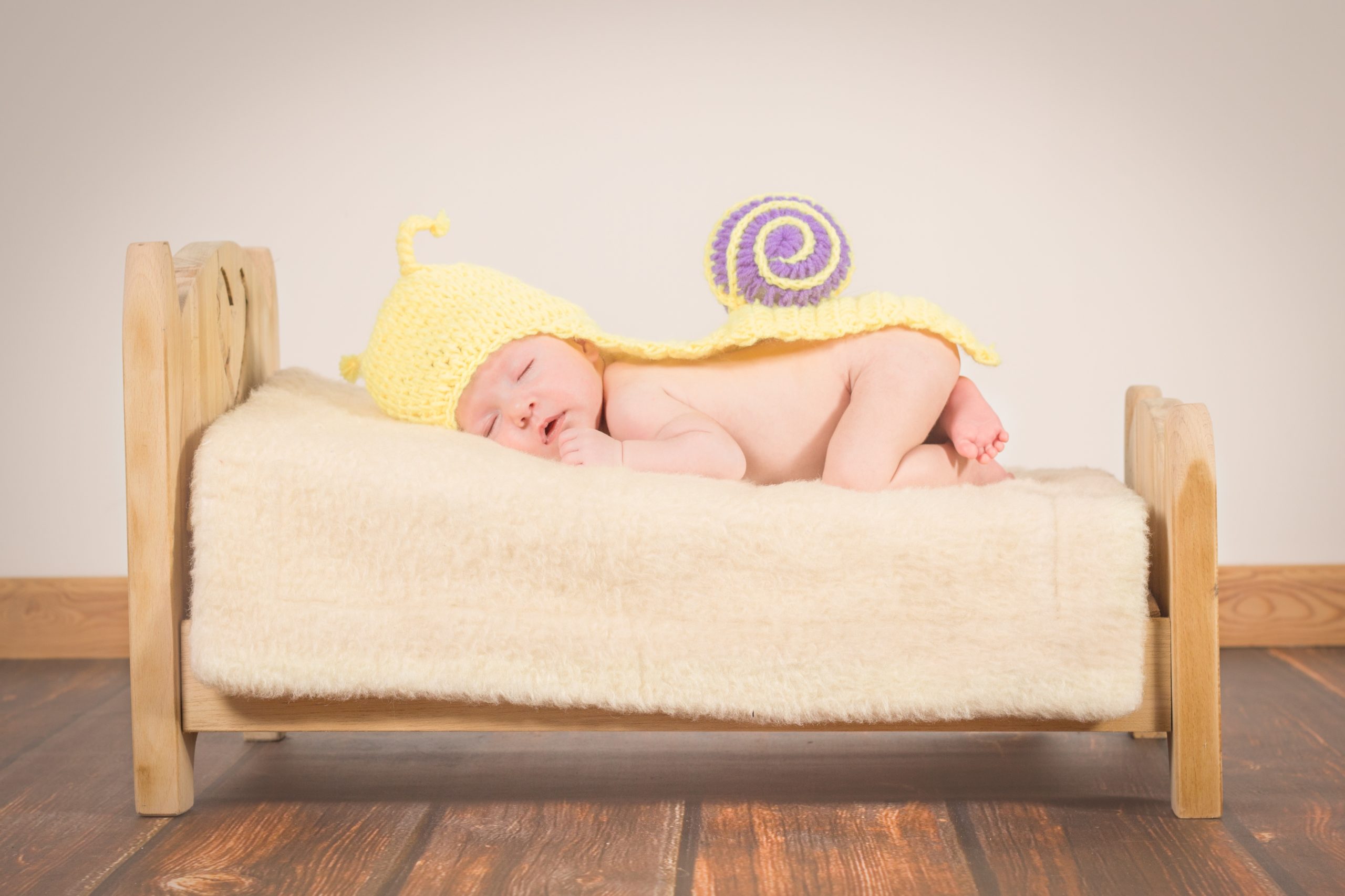 Picture of a baby asleep on a bed covered in a yellow blanket.