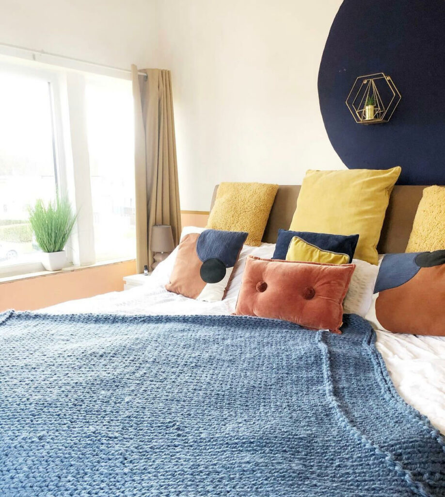 A cosy bed decorated with blue and yellow bedding.