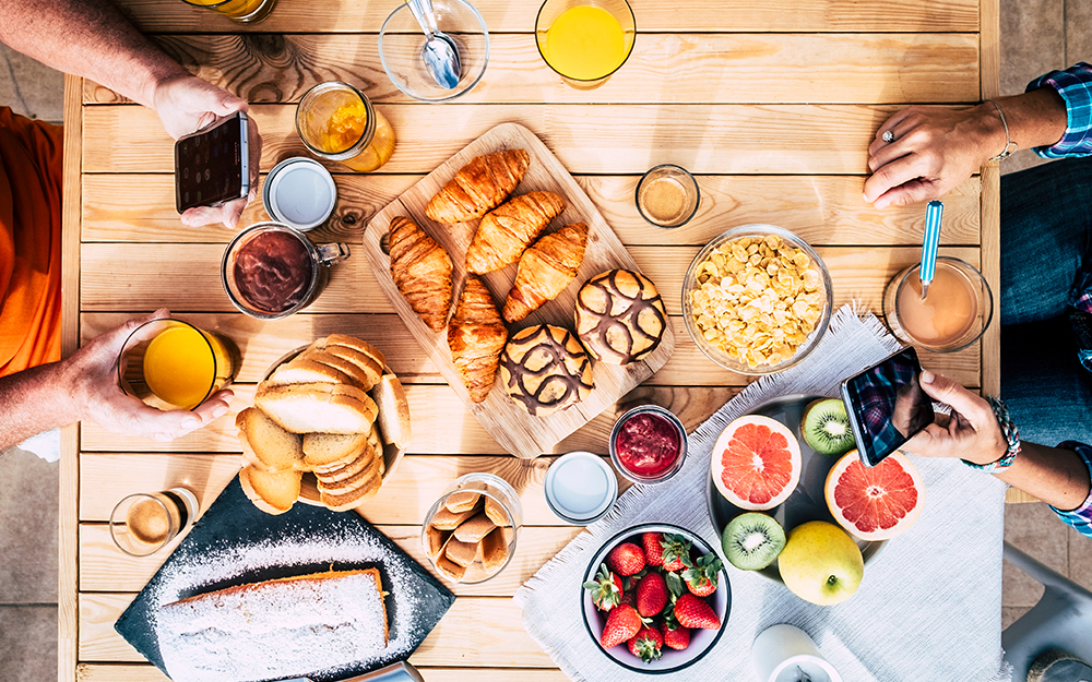 Table of breakfast things including croissants, bread, fruit, cake and drinks