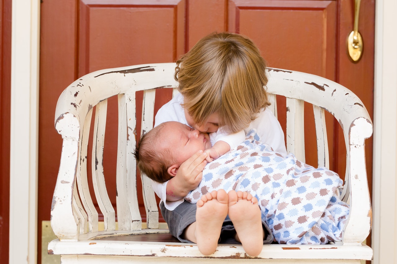 Picture of a young child kissing his baby brother.