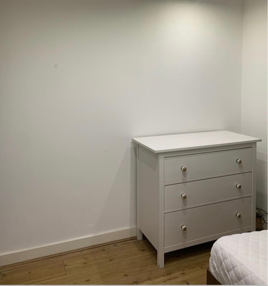 A chest of drawers next to a blank wall.