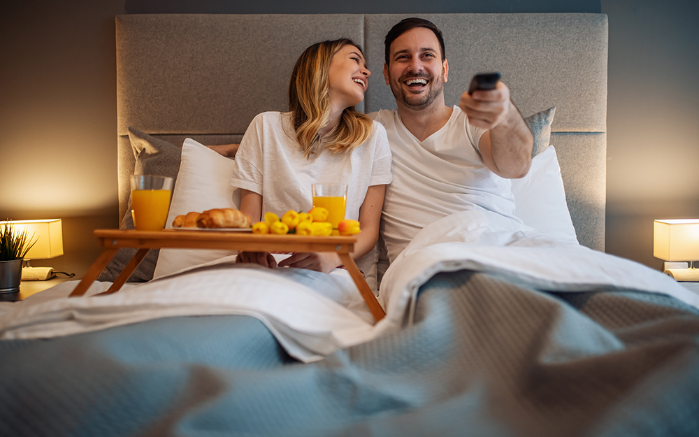 Couple watching TV in bed.