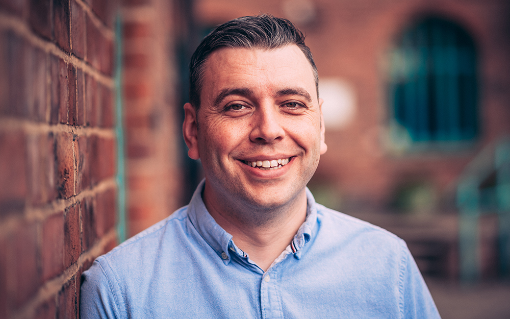 Craig Roberts, Finance Director, standing outside next to a wall smiling.