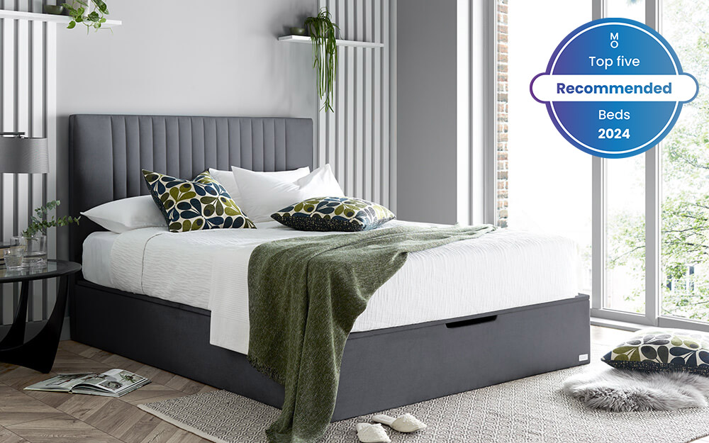 Image of the Elle Decoration Model 1 Ottoman Bed Frame with a mattress, green blanket and pillows on top. Included in the image is a badge overlay stating that this mattress is one of Mattress Online's top five recommended beds of 2024.