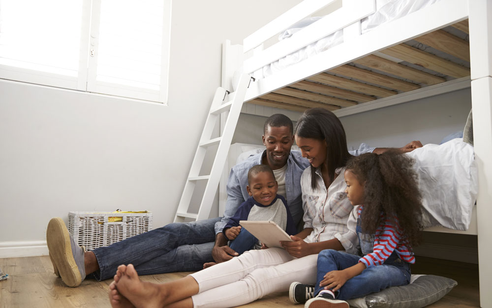 A family ready together next to a bunk bed