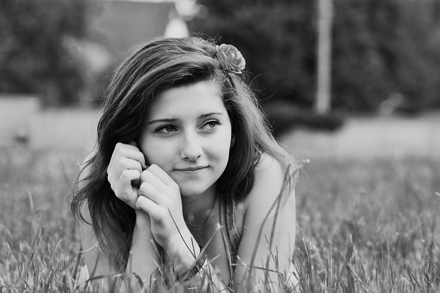 Picture of a girl looking mindful, lying down in a meadow.