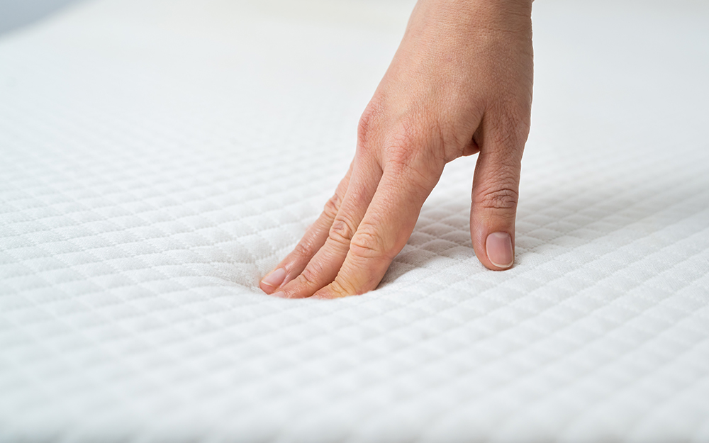 A person pressing on a mattress to feel how firm it is.