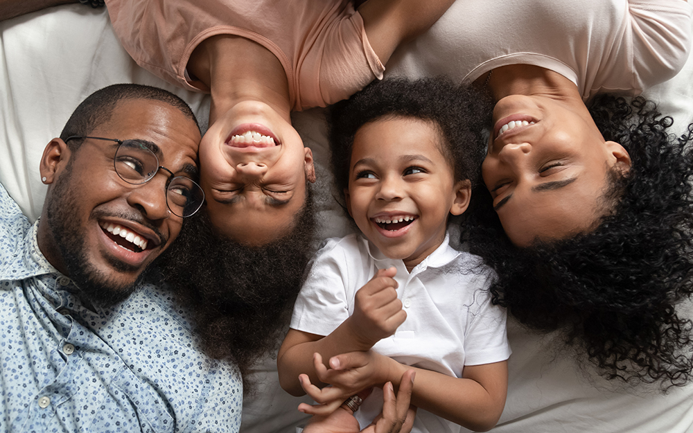 A happy family smiling on a bed