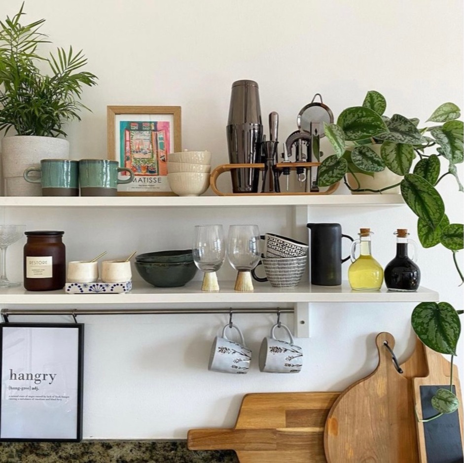 Decorated kitchen shelves with plants and decorative mugs.