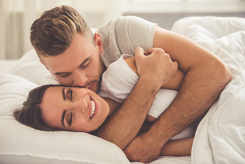 Man and woman cuddling in bed