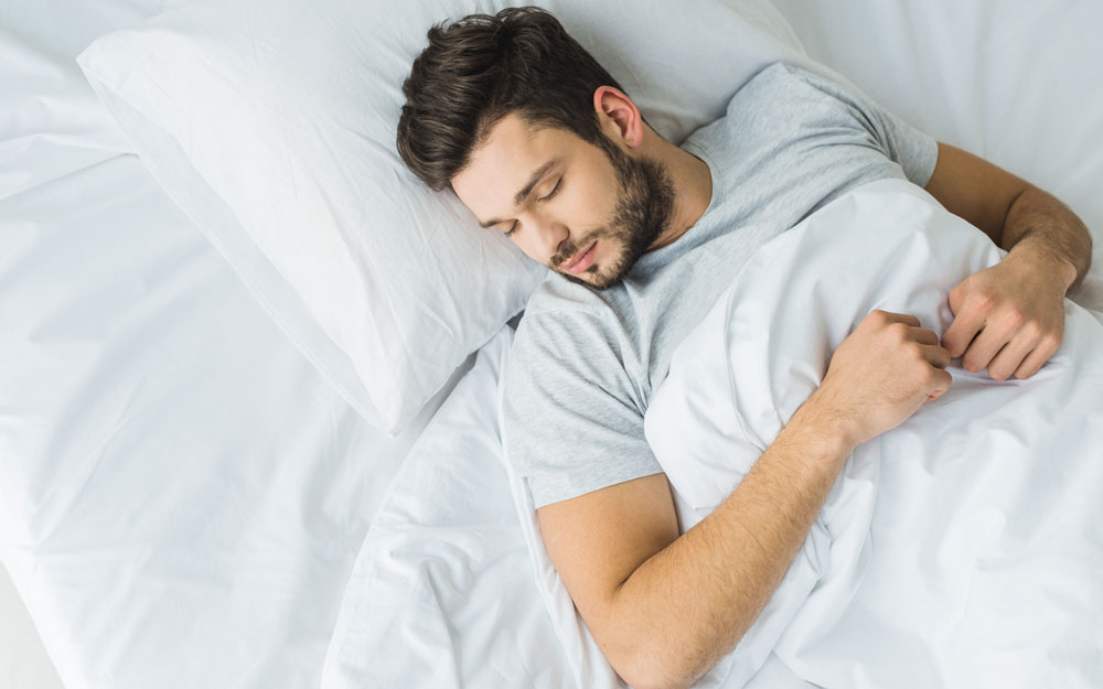 Man sleeping on his back in bed