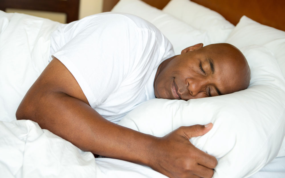 A man sleeping on his side hugging a pillow