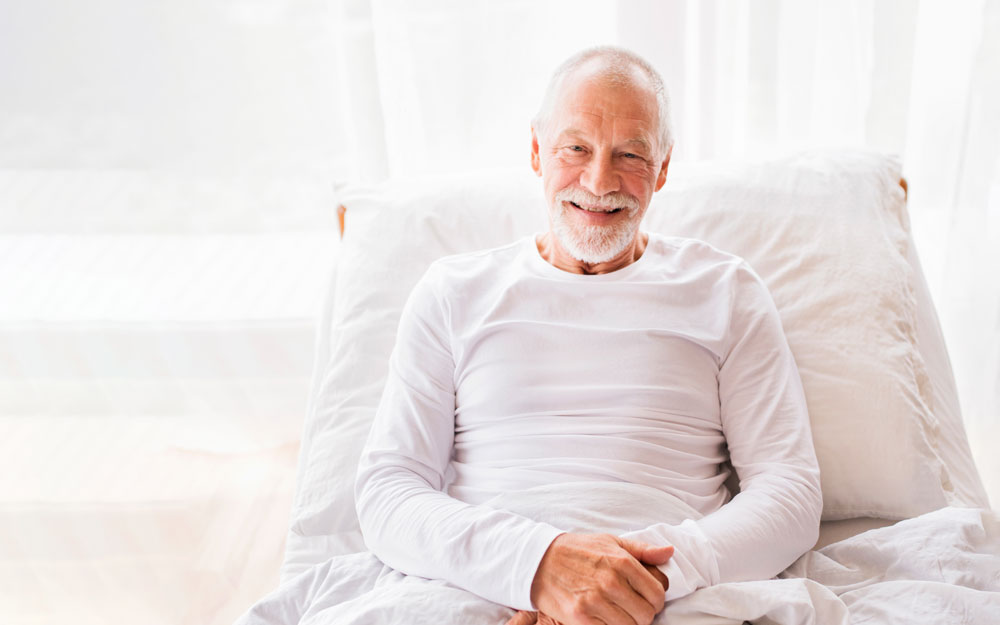 Elderly man sitting up in adjustable bed