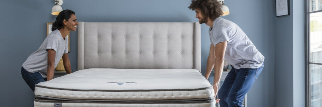 A couple putting their new mattress on a bed
