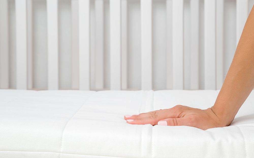 A person pressing on a mattress topper to test its firmness