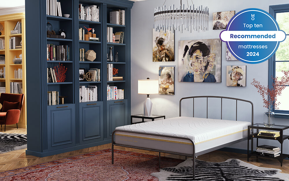 Image of the Memory Zone 3000 Pocket Mattress on top of a grey metal bed frame. Placed in a room that features art work on the walls and a blue bookshelf. Included in the image is a badge overlay stating that this mattress is one of Mattress Online's top ten recommended mattresses of 2024.