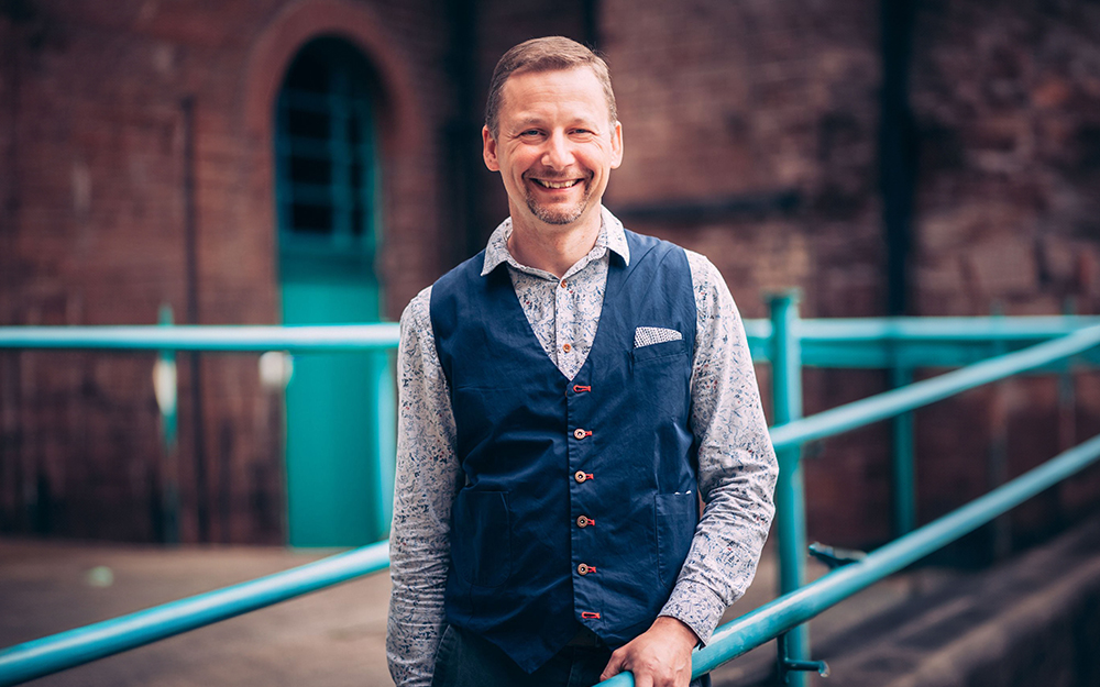 Michael Jervis, Head of Digital, standing outside leaning against a railing smiling.