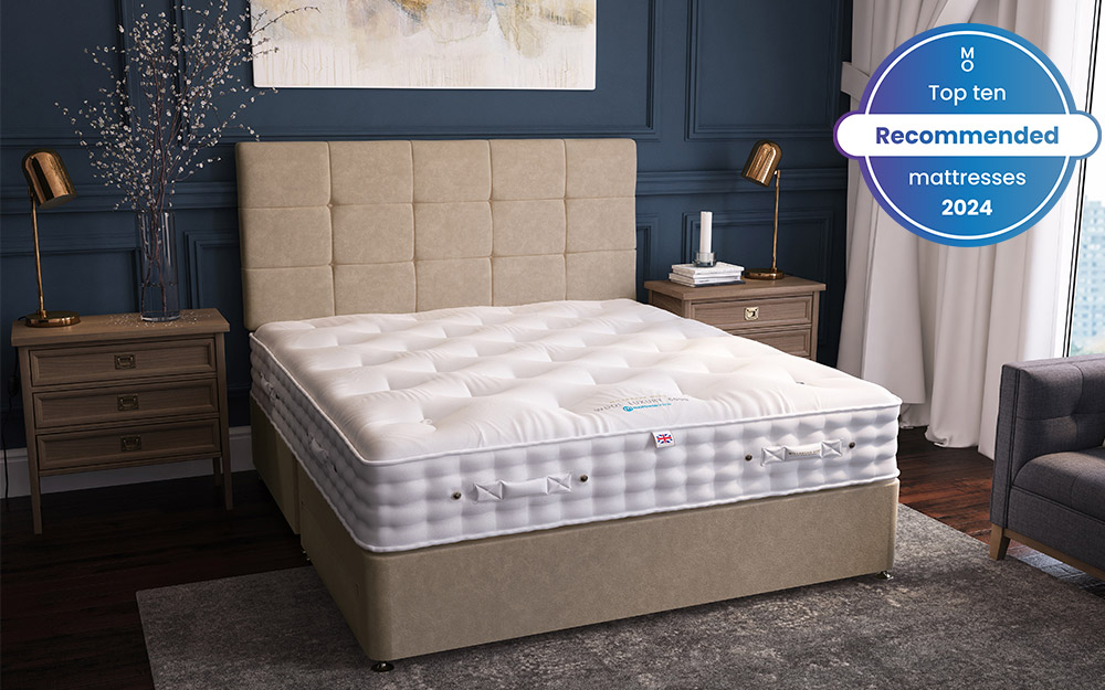 Image of the Millbrook Wool Luxury 5000 Pocket Mattress on top of a beige bed frame. To each side of the bed is bedside table with lamps. Included in the image is a badge overlay stating that this mattress is one of Mattress Online's top ten recommended mattresses of 2024.