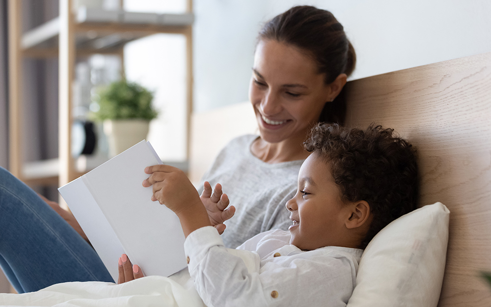 Mother reading a book with her son in bed