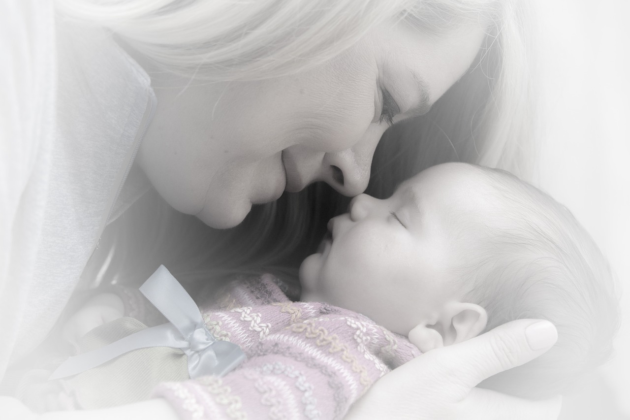 A mother looking fondly at her sleeping baby.