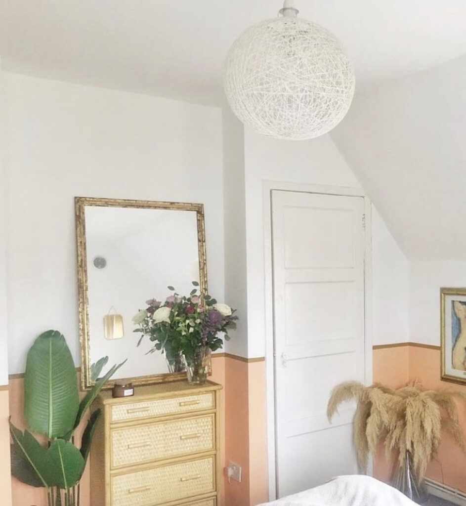 A tidy, pale pink and white bedroom.