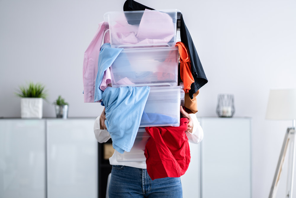 Woman holding boxes full of clothes while decluttering