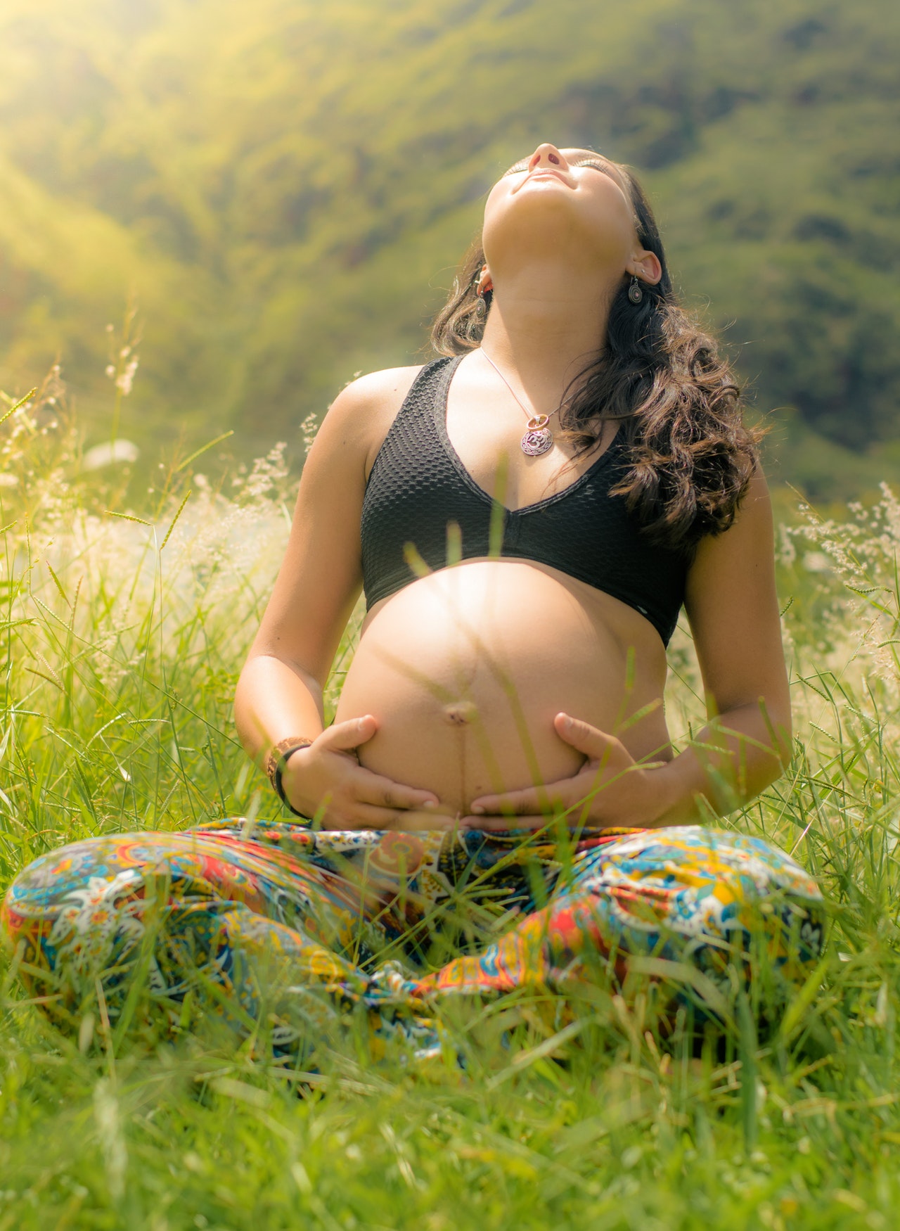 A pregnant lady sitting outside in the sun.