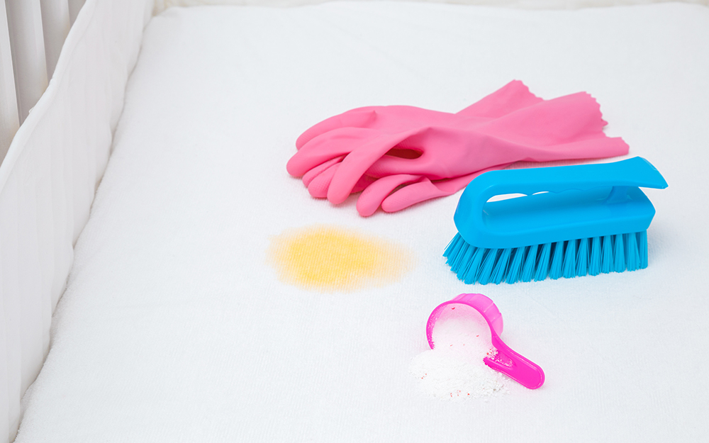 Gloves, brush and stain remover on a mattress