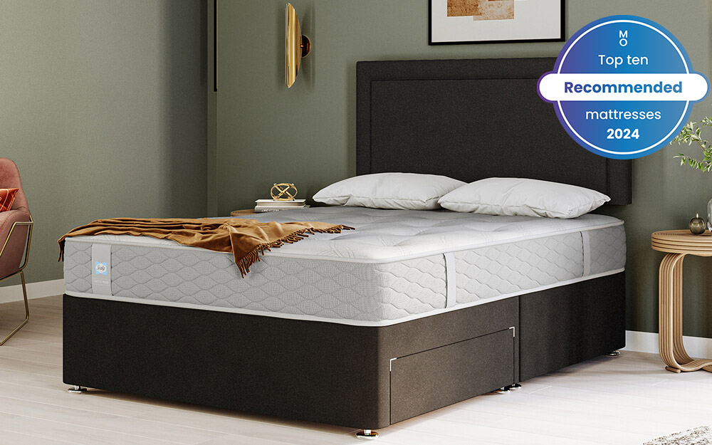 Image of the Sealy Mellbreak Ortho Plus Mattress on top of a black fabric bed. Included in the image is a badge overlay stating that this mattress is one of Mattress Online's top ten recommended mattresses of 2024.