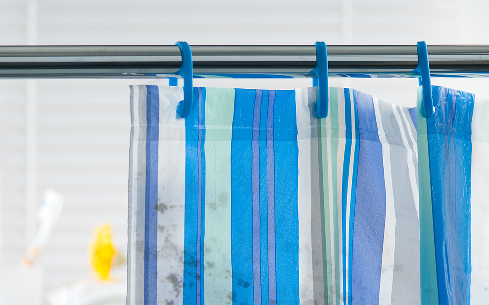 Shower curtain with black damp spots.