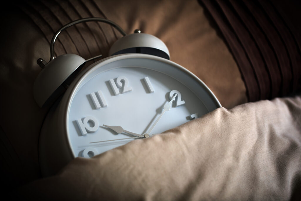 Alarm clock in bed covered with a duvet