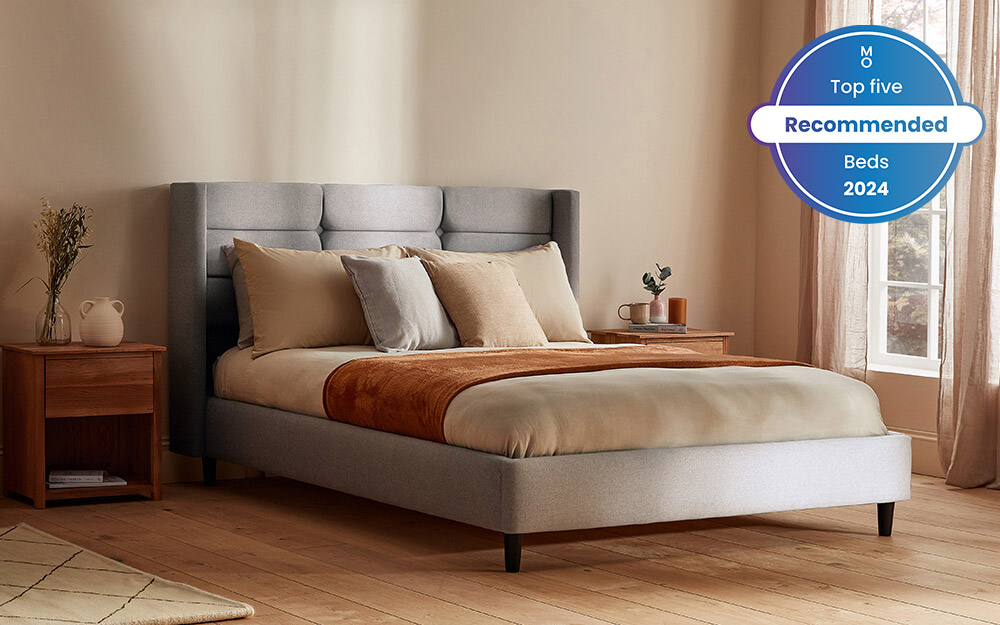 Image of the Silentnight Lilith Upholstered Bed Frame in grey with a mattress, duvet and pillows on top. Included in the image is a badge overlay stating that this mattress is one of Mattress Online's top five recommended beds of 2024.