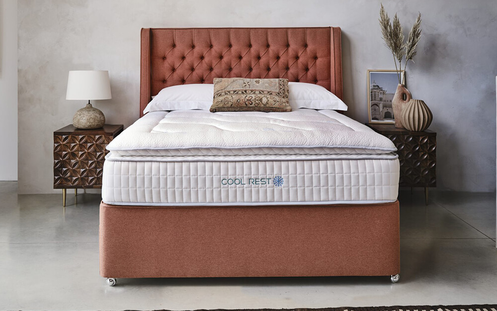 The Sleepeezee Cool Rest 2400 Pocket Pillow Top Mattress on a coral coloured divan bed.