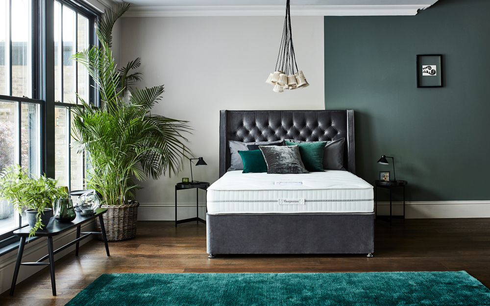 The Sleepeezee Hybrid 2000 PocketGel Mattress in a large, green bedroom on a black fabric divan bed.