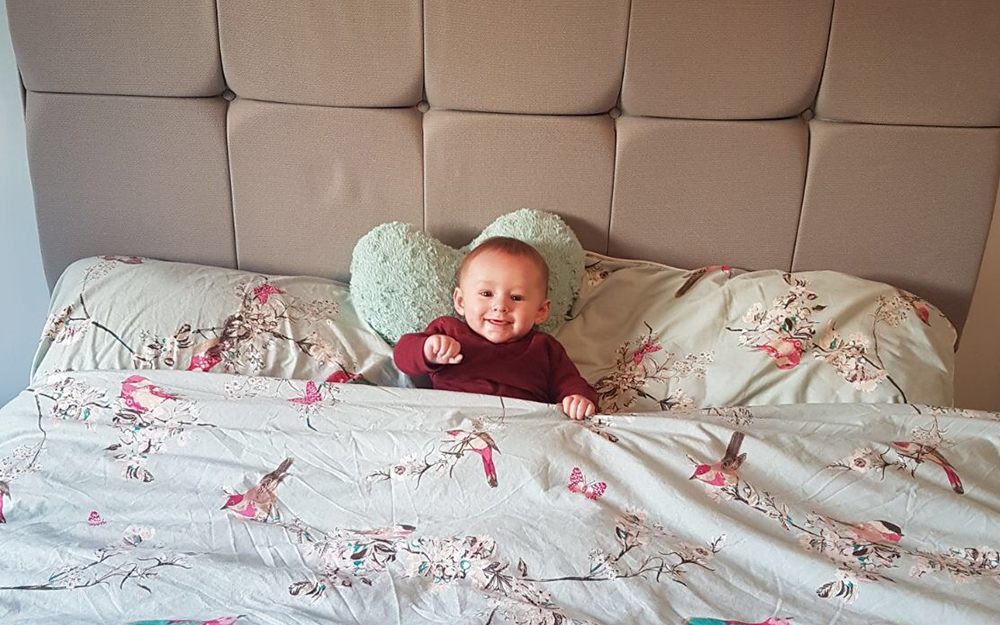 A baby sat on the Sleepeezee Memory Comfort 1000 mattress.