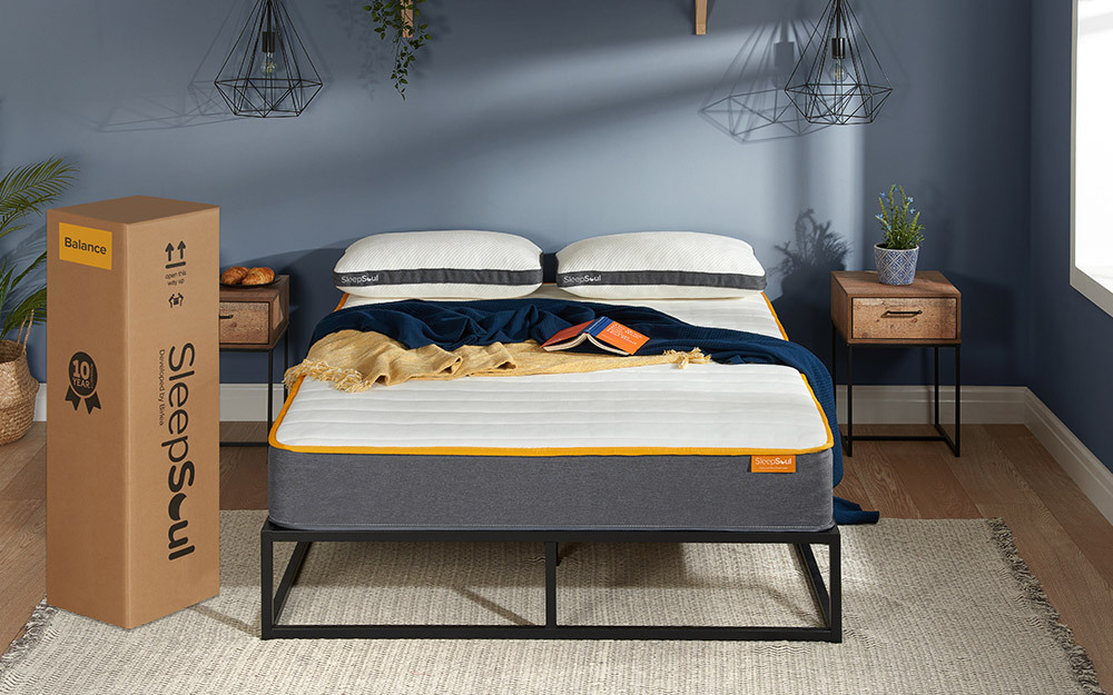 The SleepSoul Balance 800 Pocket Memory Mattress in a blue bedroom in a black metal bed frame. The mattress box is next to the bed.