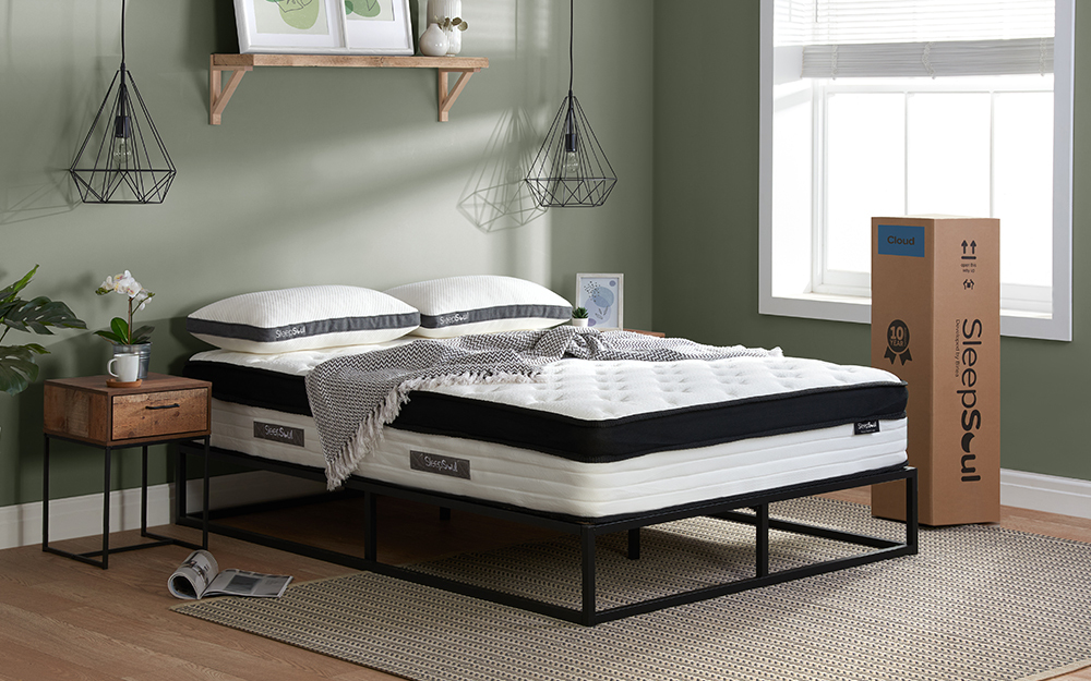 The SleepSoul Cloud 800 Pocket Memory Pillow Top Mattress in a mint green bedroom on a black metal bed. The mattress box is to the right of the bed.