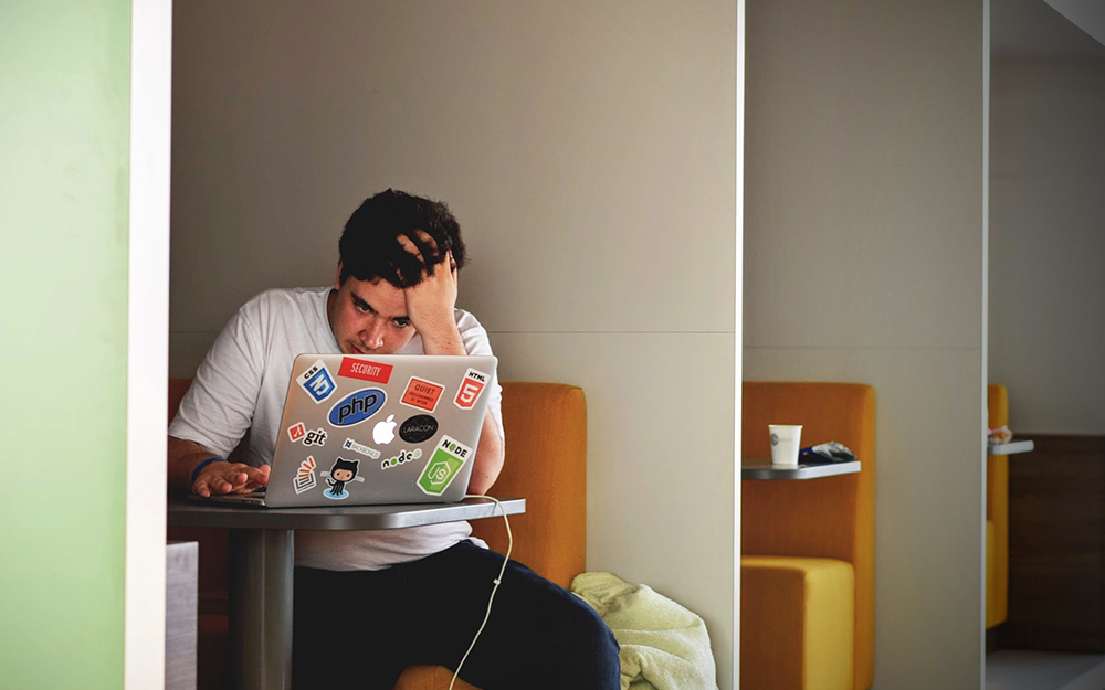 A man looking stressed at his latop screen.