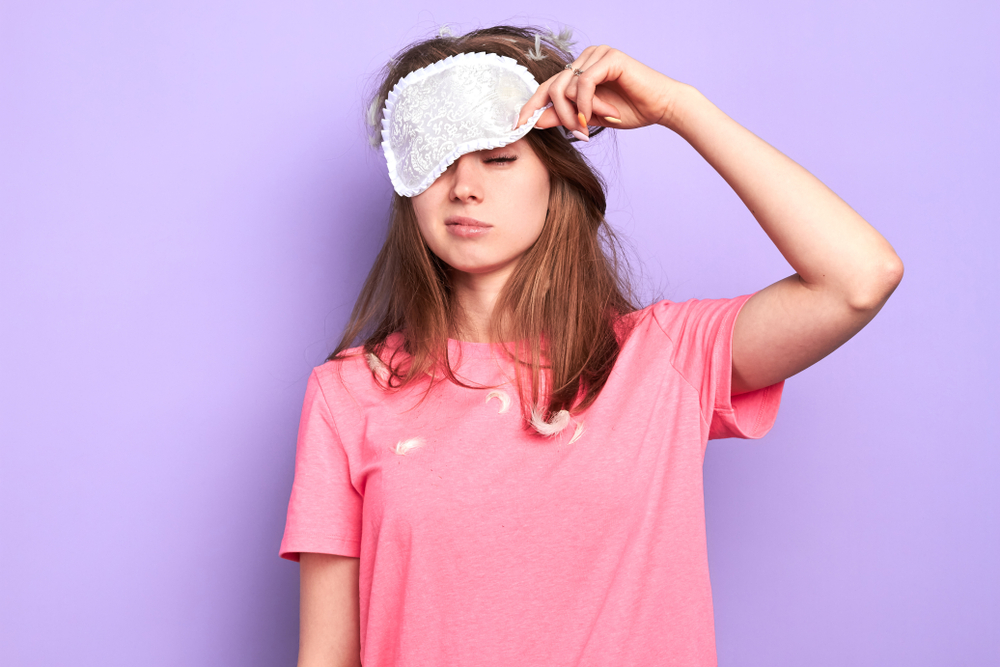 Tired woman in pink t-shirt and eyemask