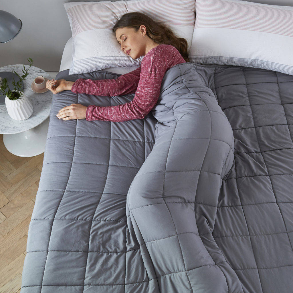 A woman sleeping under a weighted blanket