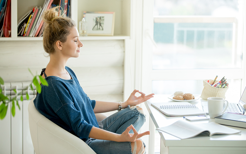 Women meditating at desk.