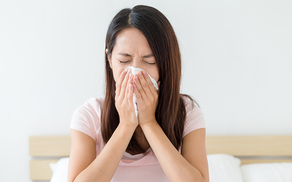 Woman sneezing on a bed