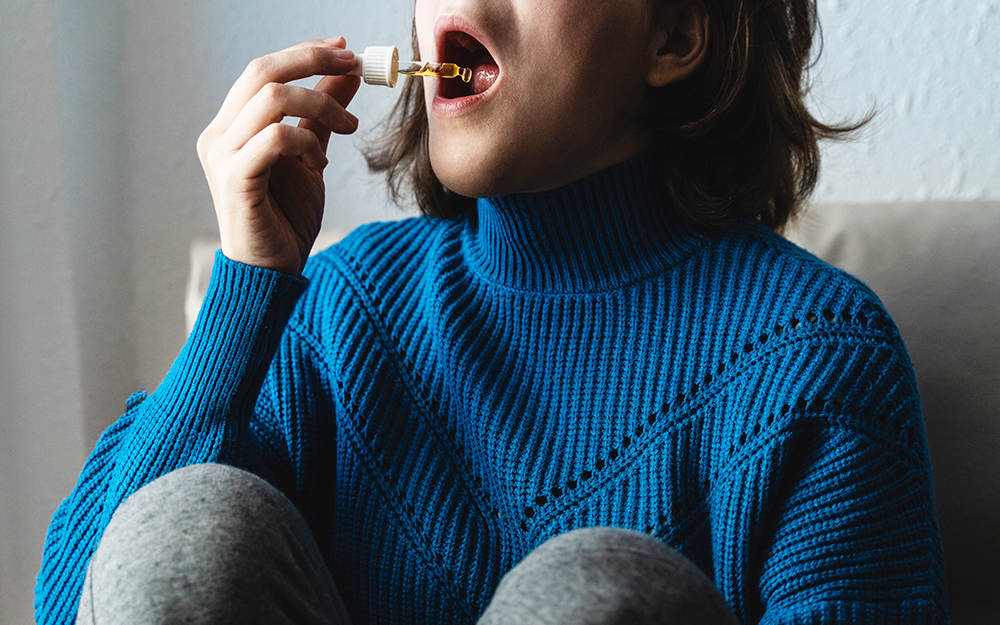 Woman using CBD oil drops at night