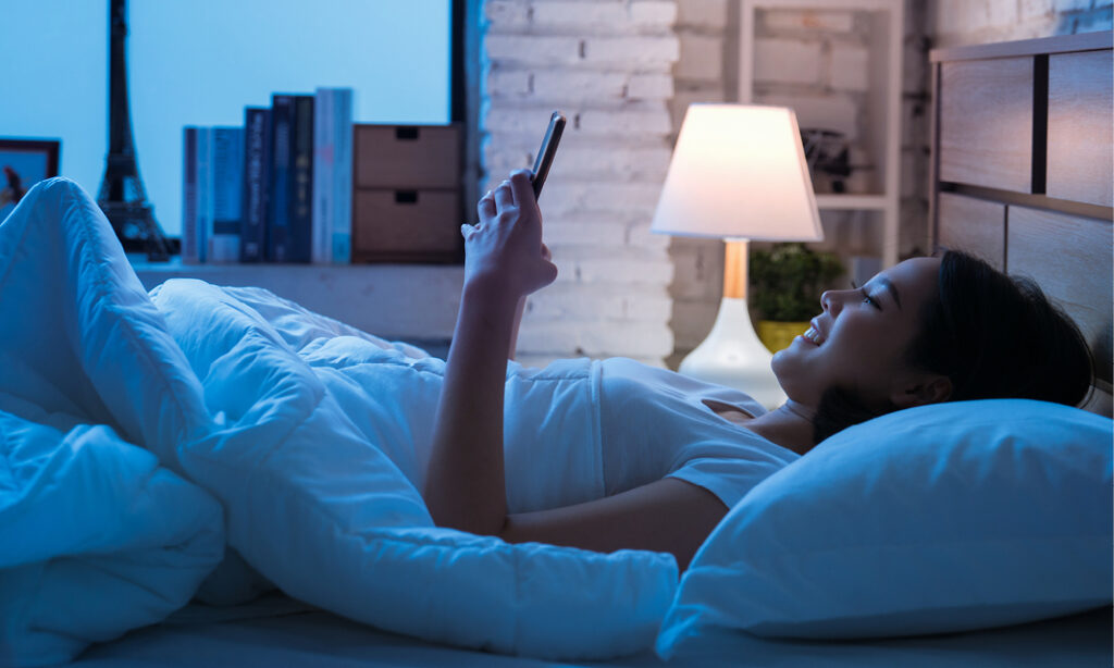 Woman using mobile phone in bed