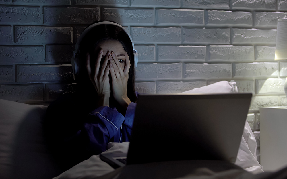 Woman watching horror film on laptop