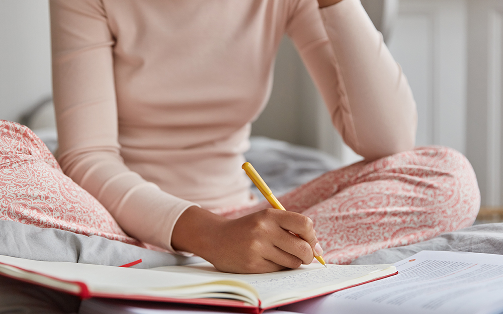 A woman in pyjamas writing in her sleep diary